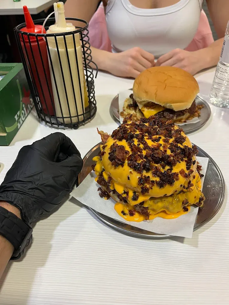 La Ankara Burger bañada en cheddar con guantes negros